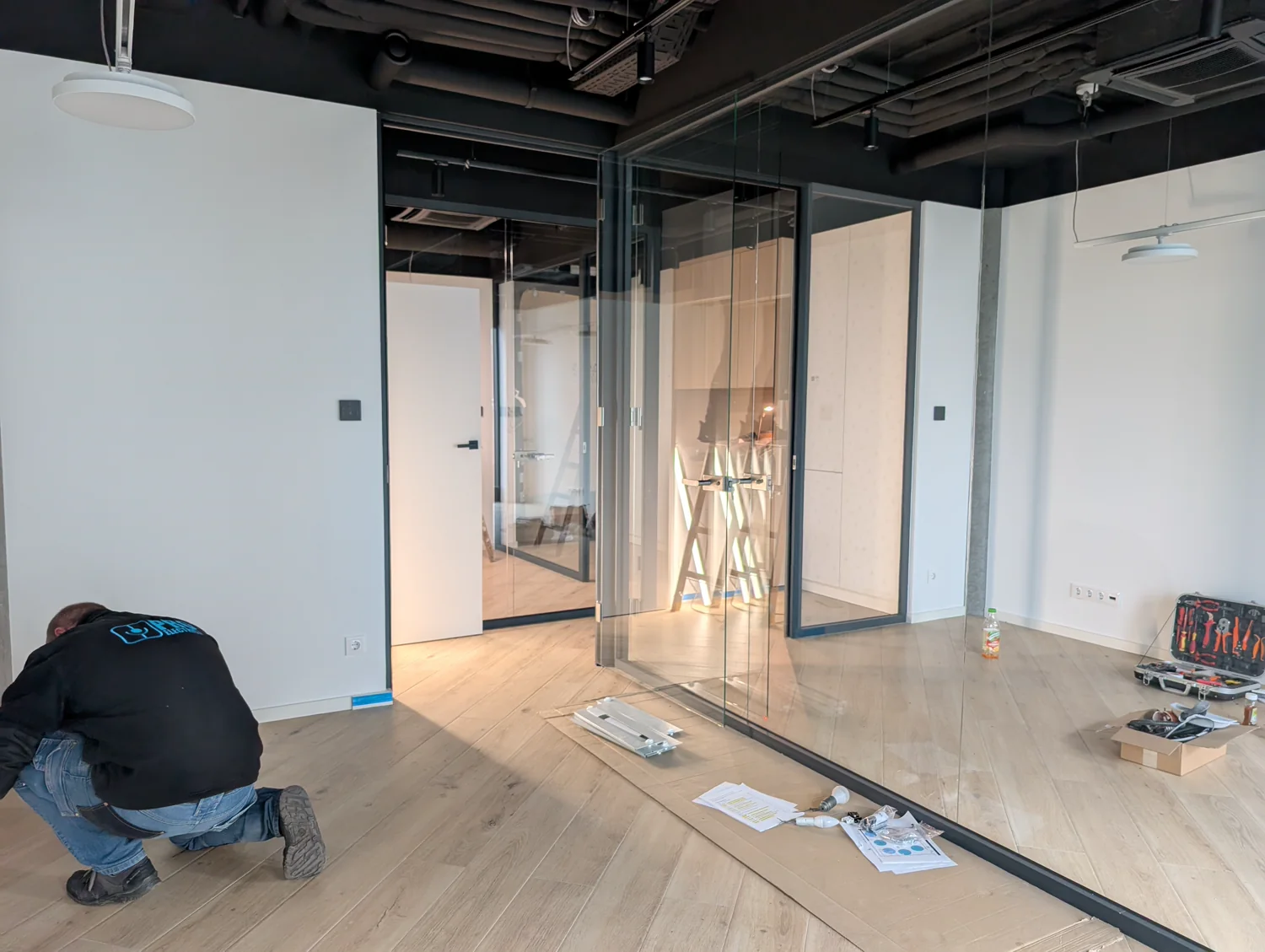 Technik PROelectrics przy instalacji w wykończonym biurze ze szklanymi ściankami